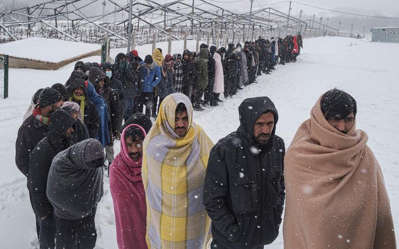 Ảnh: Xót xa cảnh người di cư quấn chăn quanh người chờ nhận thức ăn dưới mưa tuyết